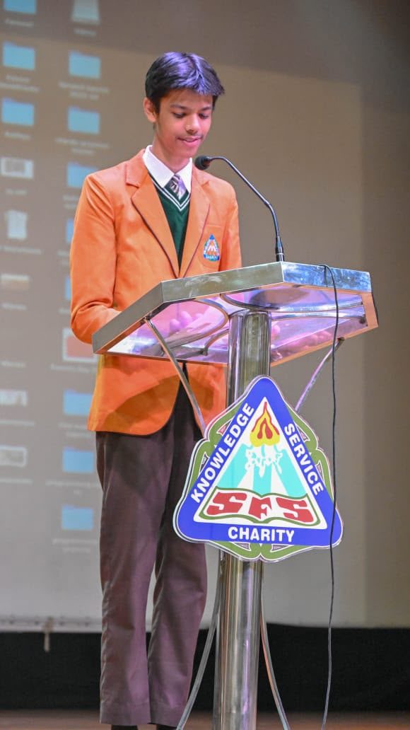 Addressing the school assembly from the podium